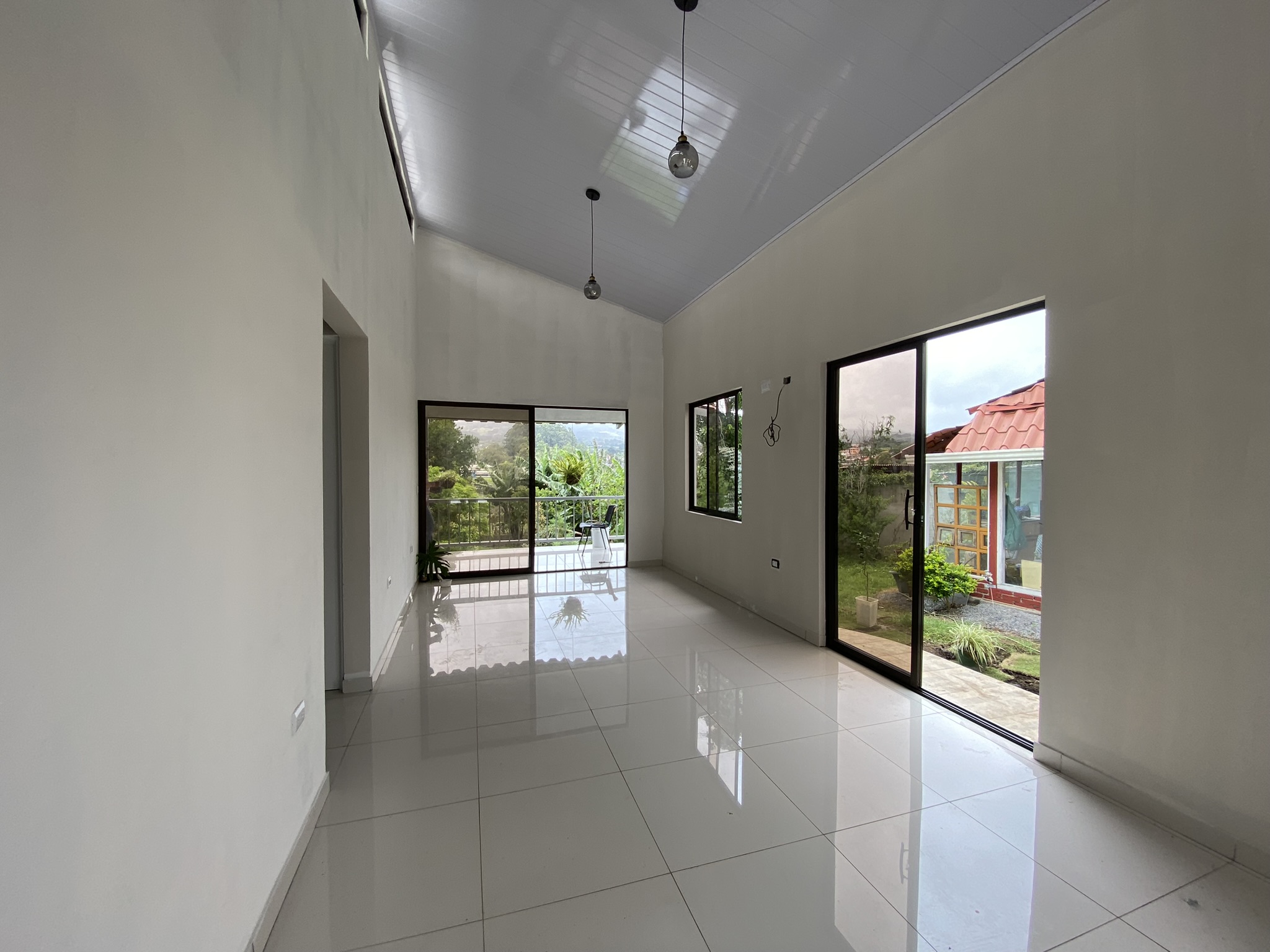 Sala amplia con techo alto, ventanales panorámicos y vista al valle, casa construida por Construeza Modular CR